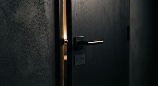 Architectural detail of a steel door handle against a matte charcoal wall