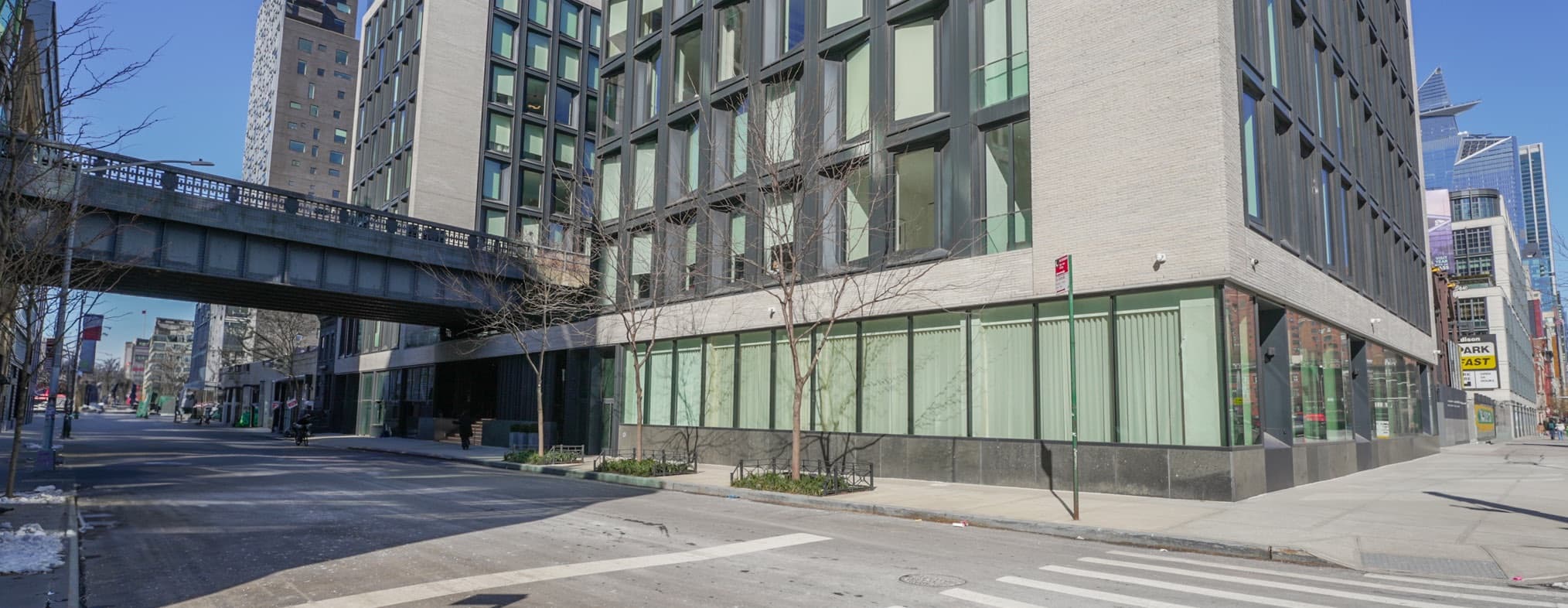 Glass storefront of 505 W 19th St at street level, with the High Line bridge crossing overhead